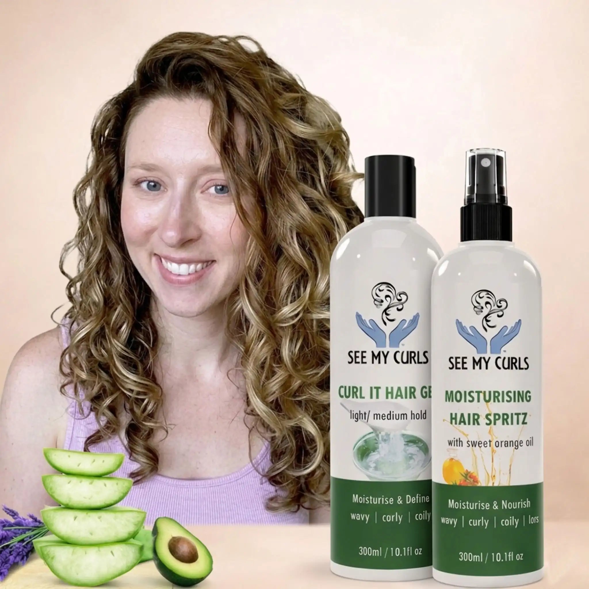 A woman with defined, bouncy blonde wavy curls smiling next to two See My Curls hair products: "Curl It Hair Gel" and "Moisturising Hair Spritz." The image features fresh aloe vera slices and avocado in the foreground, highlighting natural ingredients for wavy, curly, and coily hair types.