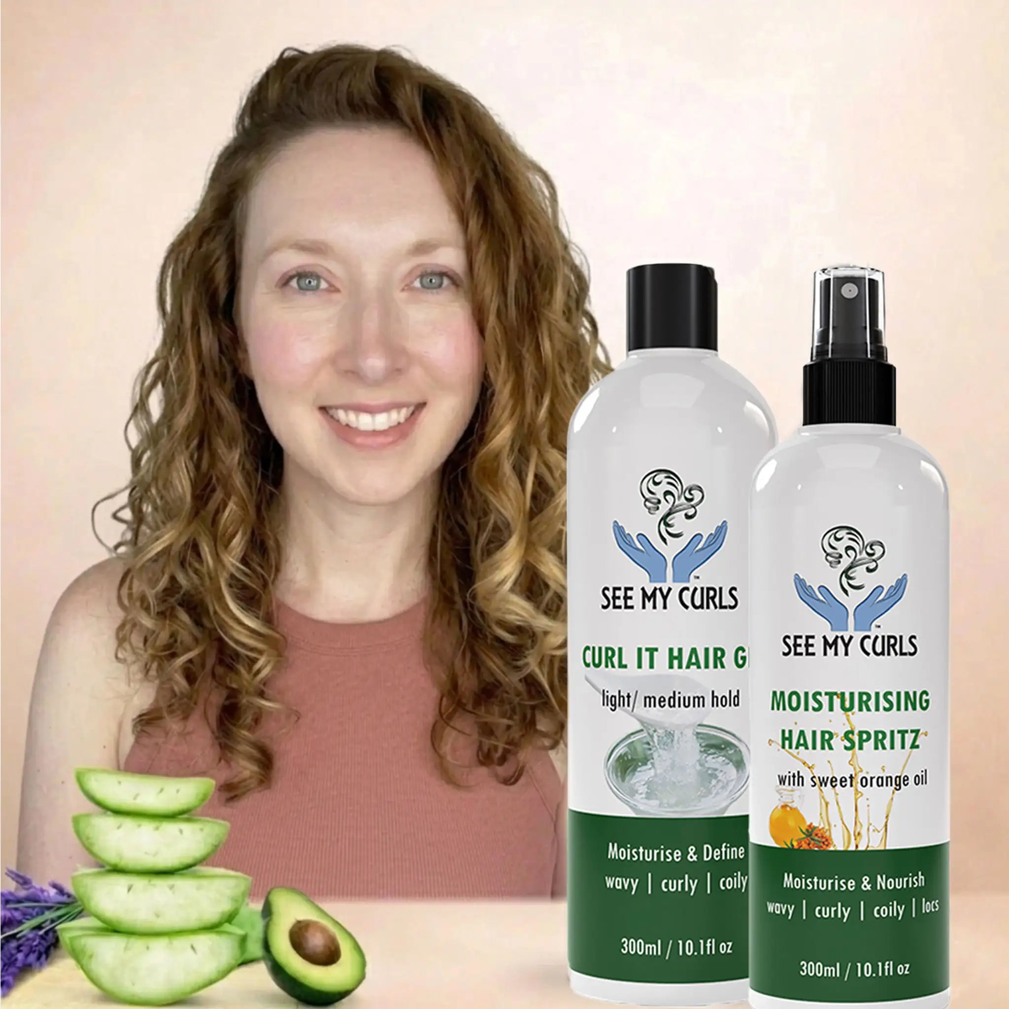 A woman with defined, bouncy blonde wavy curls smiling next to two See My Curls hair products: "Curl It Hair Gel" and "Moisturising Hair Spritz." The image features fresh aloe vera slices and avocado in the foreground, highlighting natural ingredients for wavy, curly, and coily hair types.